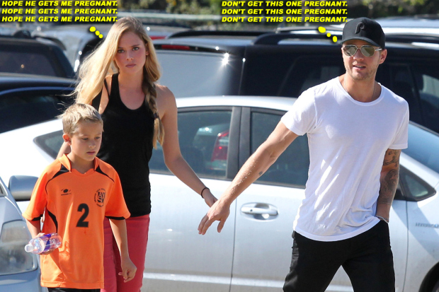 Ryan Phillippe cheers on his son Deacon whilst his girlfriend Paulina Slagter sits nearby and reads "The New Jim Crow"