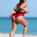 Plus model Jolena Forde busts out of her Baywatch babe red one-piece bathing suit as she rescues Russian rapper GeeGun Denis Ustimenko-Vainstein filming his new music video in Miami Beach, Florida