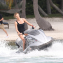 Charlize Theron wears a black one piece bikini as she hits the waves on a jet ski in Miami
