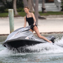 Charlize Theron wears a black one piece bikini as she hits the waves on a jet ski in Miami