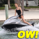 Charlize Theron wears a black one piece bikini as she hits the waves on a jet ski in Miami